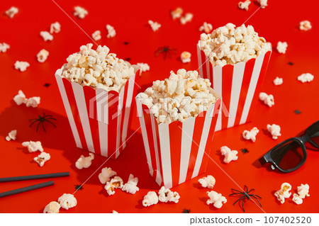 Striped boxes with popcorn on a red background Striped boxes with popcorn on a red background 107402520