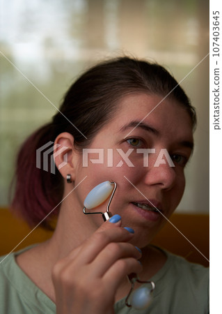 Woman is massaging her face roller. Woman is massaging her face roller. 107403645