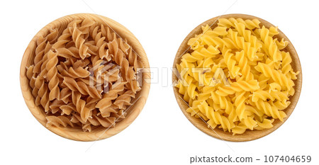 Wolegrain fusilli pasta from durum wheat in wooden bowl isolated on white background with full depth of field. Top view. Flat lay. 107404659