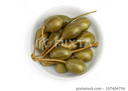Capers in ceramic bowl isolated on white background. Pickled or canned capers. Top view. Flat lay Capers in ceramic bowl isolated on white background. Pickled or canned capers. Top view. Flat lay 107404756