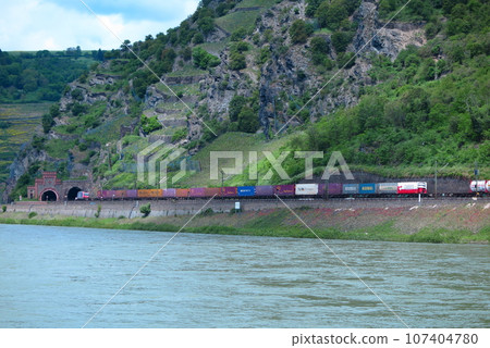 Freight train running through the mountains along the Rhine River 107404780
