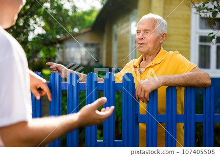 Good neighbors talk on border of their farms Good neighbors talk on border of their farms 107405508