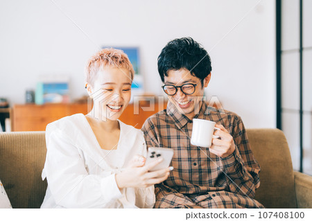 Couple looking at a smartphone together Couple looking at a smartphone together 107408100