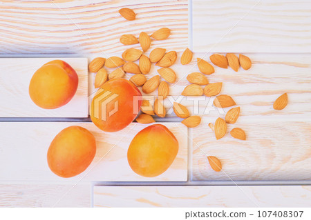 Fresh ripe apricot fruits with kernels on wooden plank surface Fresh ripe apricot fruits with kernels on wooden plank surface 107408307