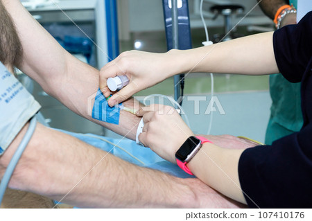 Inserting a catheter into a vein in a patient's arm before surgery. Inserting a catheter into a vein in a patient's arm before surgery. 107410176