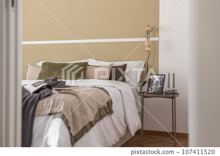 Side shot of edge of large cozy double bed with a bedside table in beige color in a hotel room. The concept of comfortable living in a business hotel with a convenient location and five-star service 107411520