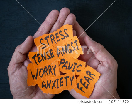 Hands hold pieces of paper with words worry, stress panic and anxiety. 107411870