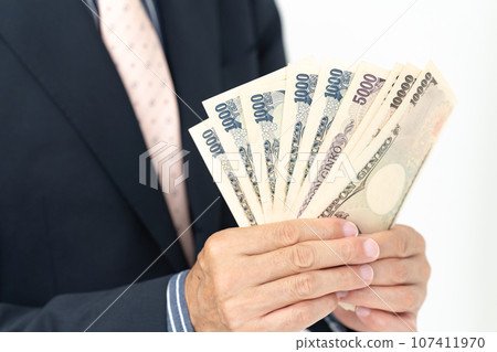 A man in a suit holding money 107411970