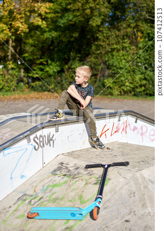 Child on kick scooter in park. Kids learn to skate roller board. Little boy skating on sunny summer day. Outdoor activity for children on safe residential street. Active sport for preschool kid. boy Child on kick scooter in park. Kids learn to skate roller board. Little boy skating on sunny summer day. Outdoor activity for children on safe residential street. Active sport for preschool kid. boy 107412513