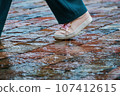 walking through a puddle in the rain. a passerby's foot on the paving stones. 107412615