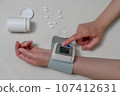 woman checking blood pressure and heart rate monitor with digital pressure gauge. Healthcare and medical concept 107412631