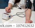 a woman suffering from high blood pressure uses a tonometer. 107412632