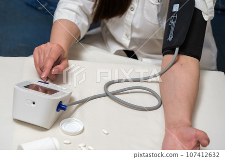 a woman suffering from high blood pressure uses a tonometer. 107412632