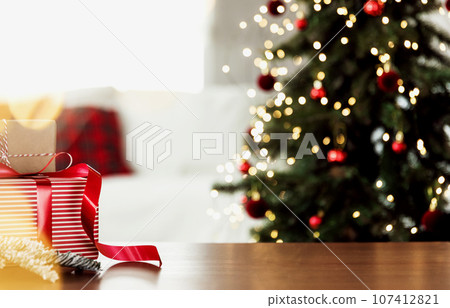 Christmas, New Year background with copy space for design. Empty wooden tabletop surface, blurred Christmas fir tree composition, bokeh sparkle lights effect. Mockup ready for product montage 107412821