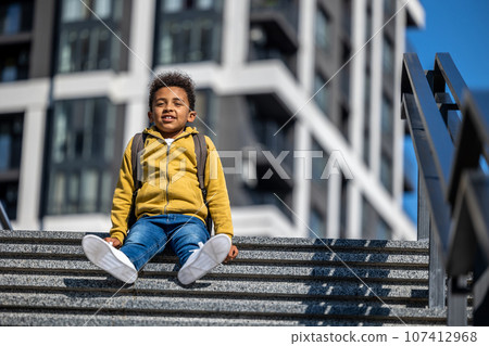 Cute schoolboy sitting on the steps and resting Cute schoolboy sitting on the steps and resting 107412968