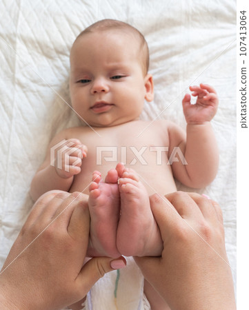 Baby's feet in maternal hands for comfort. Concept of constipation relief techniques 107413064
