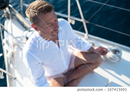 Man sitting in a lotus pose and meditating Man sitting in a lotus pose and meditating 107413091