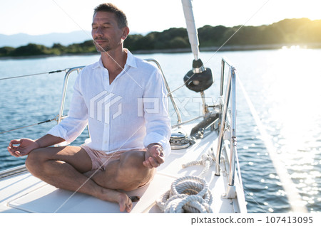 Man sitting in a lotus pose and meditating Man sitting in a lotus pose and meditating 107413095