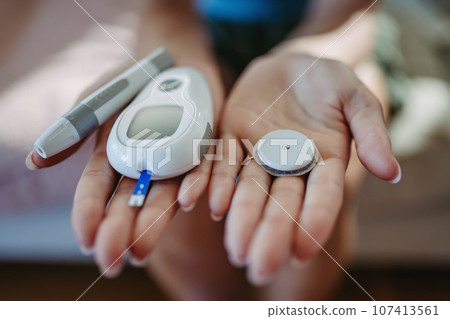Close up of hands with diabetes supplies and devices. Close up of hands with diabetes supplies and devices. 107413561