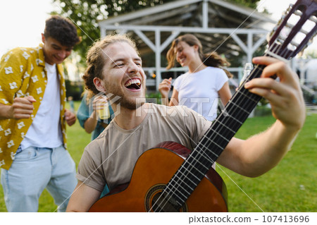 Handsome man playing at guitar at garden party. Handsome man playing at guitar at garden party. 107413696