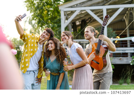 Friends taking selfie at a summer grill garden party. 107413697