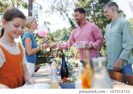 Family setting table for summer garden party. 107413733