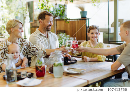 Big family with children and a small baby making toast at family dinner in a restaurant. 107413766