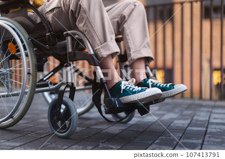 Close up of young gen Z boy in a wheelchair in the city. Close up of young gen Z boy in a wheelchair in the city. 107413791
