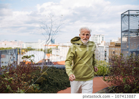 Senior man running outdoors in the city. 107413887