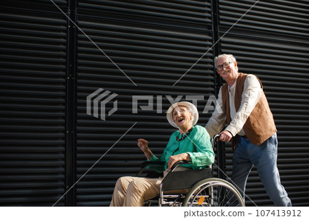 Elderly man pushing his lovely wife in wheelchair. 107413912