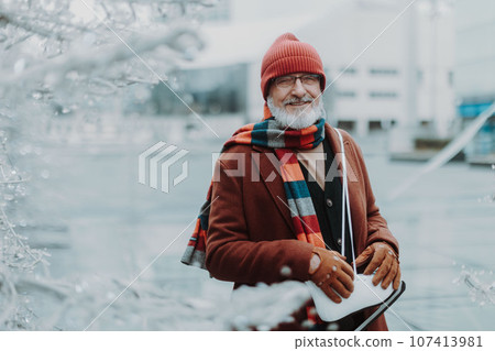 Portrait of senior man in winter at outdoor ice skating rink. 107413981