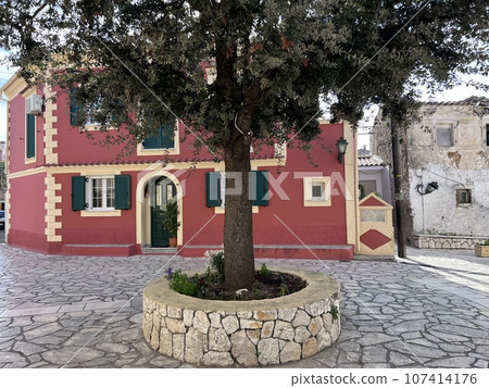 Red house in stoned streen in Corfu island, Greece. Tree Red house in stoned streen in Corfu island, Greece. Tree 107414176