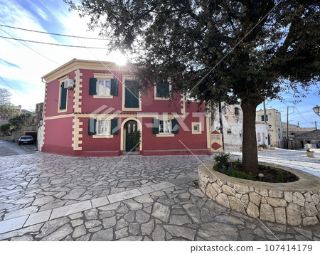 Red house in stoned streen in Corfu island, Greece. Tree Red house in stoned streen in Corfu island, Greece. Tree 107414179
