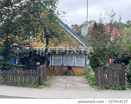 Traditional colorful yellow wooden architecture in Nida, Lithuania, wood painted building exterior detail. Bicycle Traditional colorful yellow wooden architecture in Nida, Lithuania, wood painted building exterior detail. Bicycle 107414237