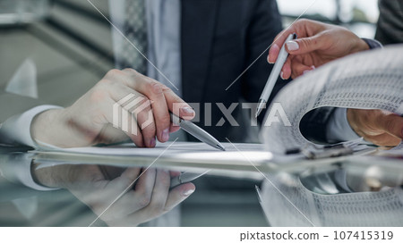 Close-up. Businessman looking at financial report and making notes with a pen in it 107415319