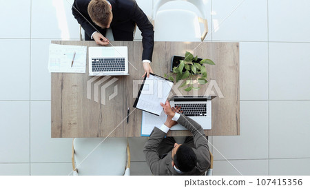 Two successful smiling businessmen are working on a laptop. view from above 107415356