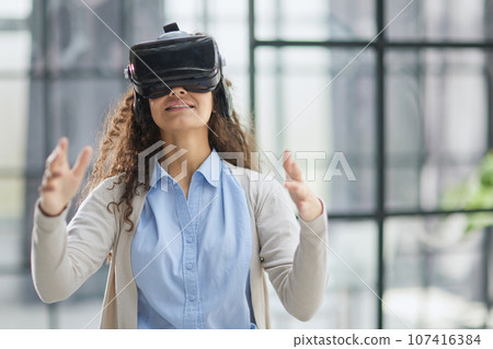 positive woman wearing virtual reality goggles headsetConnection, technology, new generation, progress concept. positive woman wearing virtual reality goggles headsetConnection, technology, new generation, progress concept. 107416384