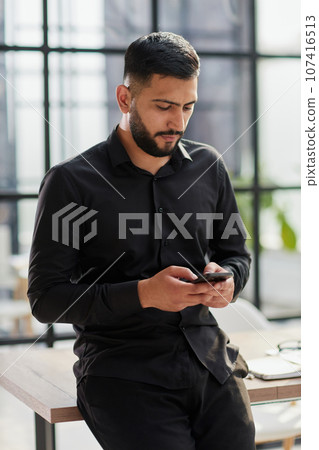 Young casual Businessman holding and using smartphone for sms messages Young casual Businessman holding and using smartphone for sms messages 107416513