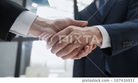 Close up of handshake on blurry conference room interior background. Partnership concept 107416931