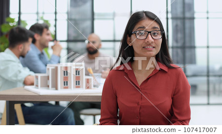 Confident business woman sitting in front of colleagues in the office Confident business woman sitting in front of colleagues in the office 107417007