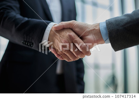 Two diverse professional business men executive leaders shaking hands at office meeting 107417314