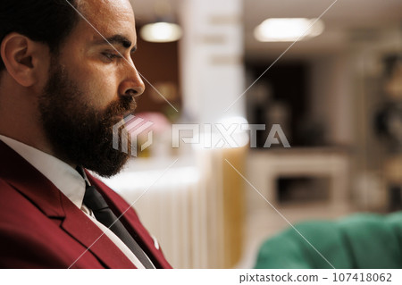 Entrepreneur sitting in lounge area, working on laptop before attending upcoming meeting with business partners. White collar worker travelling for work to forge new collaborations. 107418062