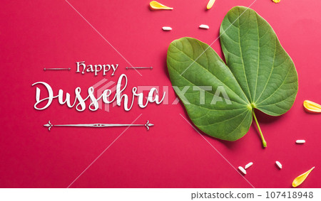 Happy Dussehra background concept made from green leaf on red paper background. Dussehra Indian Festival concept. 107418948