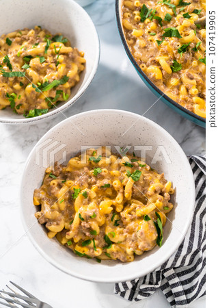 Serving homemade hamburger helper in white ceramic bowls. Serving homemade hamburger helper in white ceramic bowls. 107419905