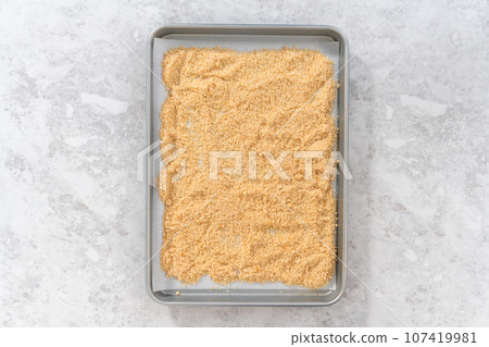 Flat lay. Spreading bread crumbs on a baking sheet lined with parchment paper to prepare dried bread crumbs. Flat lay. Spreading bread crumbs on a baking sheet lined with parchment paper to prepare dried bread crumbs. 107419981