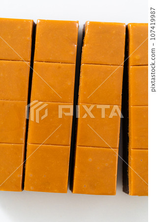 Cutting caramel fudge into square pieces on a white cutting board. Cutting caramel fudge into square pieces on a white cutting board. 107419987