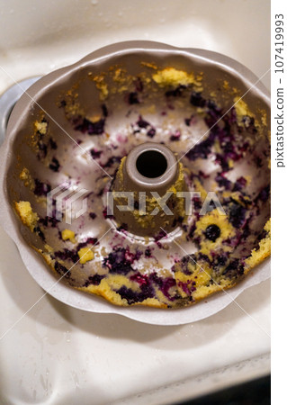 Soaking dirty aluminum bundt cake pan with soapy water in a kitchen sink. Soaking dirty aluminum bundt cake pan with soapy water in a kitchen sink. 107419993