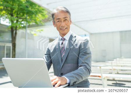 Senior man using a computer outdoors Senior man using a computer outdoors 107420037