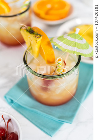 Freshly made Sunset cocktail garnished with a slice of fresh orange and pineapple. 107420181