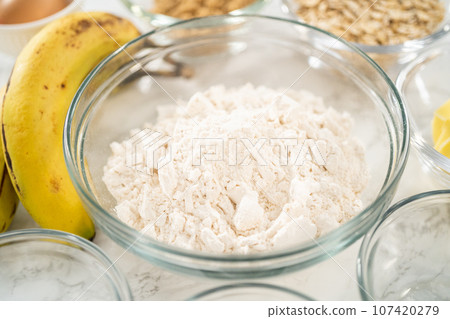 Measured ingredients in glass mixing bowls to bake banana oatmeal muffins. 107420279